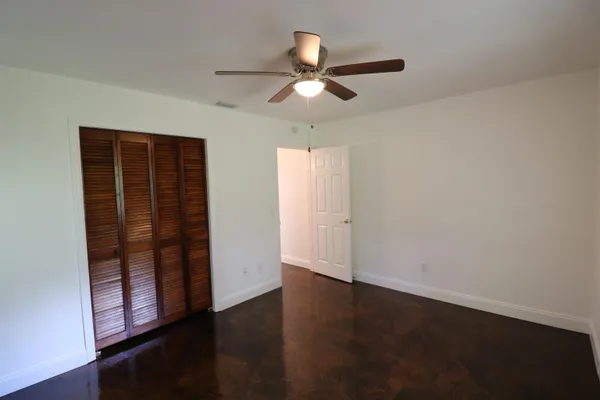 an empty room with wooden floor cabinet and windows
