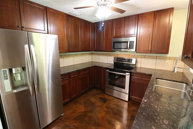 a kitchen with granite countertop stainless steel appliances and refrigerator