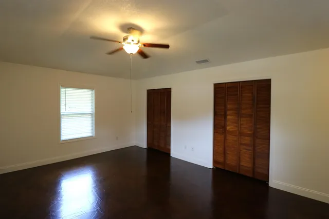 a view of empty room with wooden floor and fan