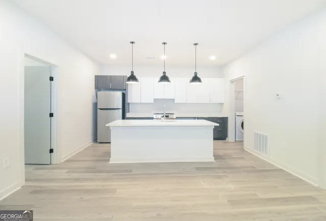 a view of kitchen with kitchen island white cabinets and stainless steel appliances