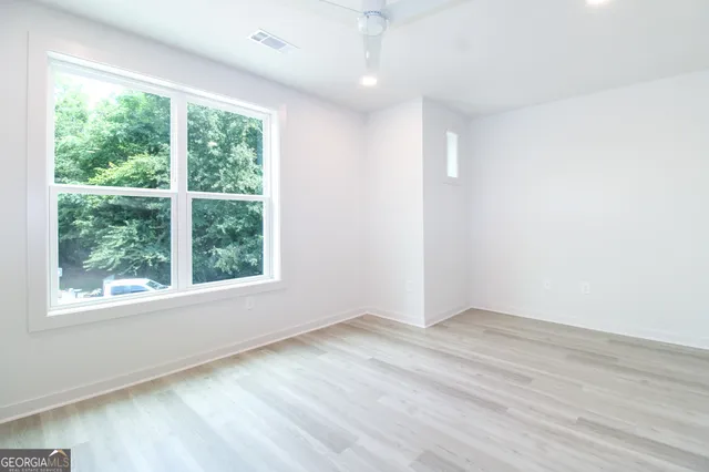 an empty room with wooden floor and windows