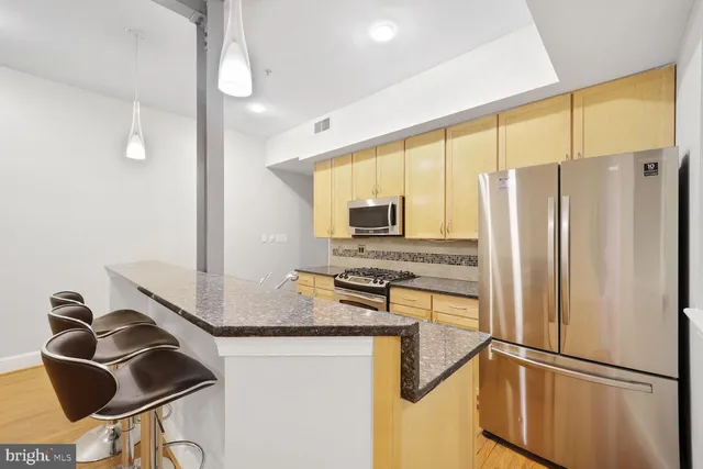 a kitchen with stainless steel appliances granite countertop a refrigerator a stove and a sink with wooden floor