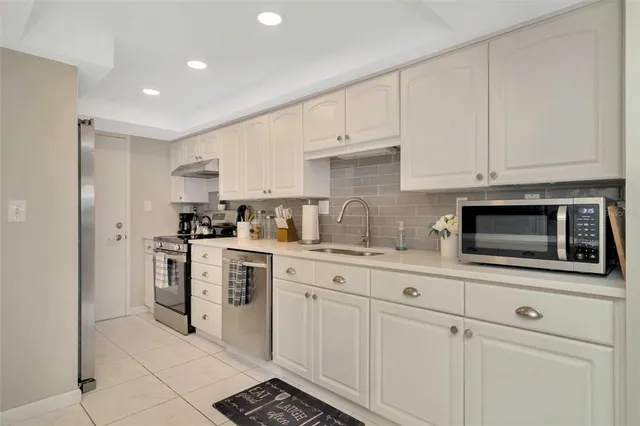 a kitchen with stainless steel appliances granite countertop a sink a stove and white cabinets