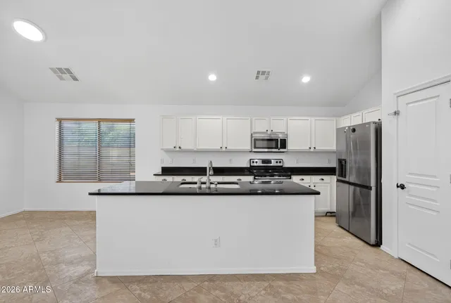 a kitchen with stainless steel appliances granite countertop a stove a refrigerator a sink and white cabinets