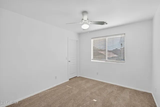 an empty room with a window and a fan