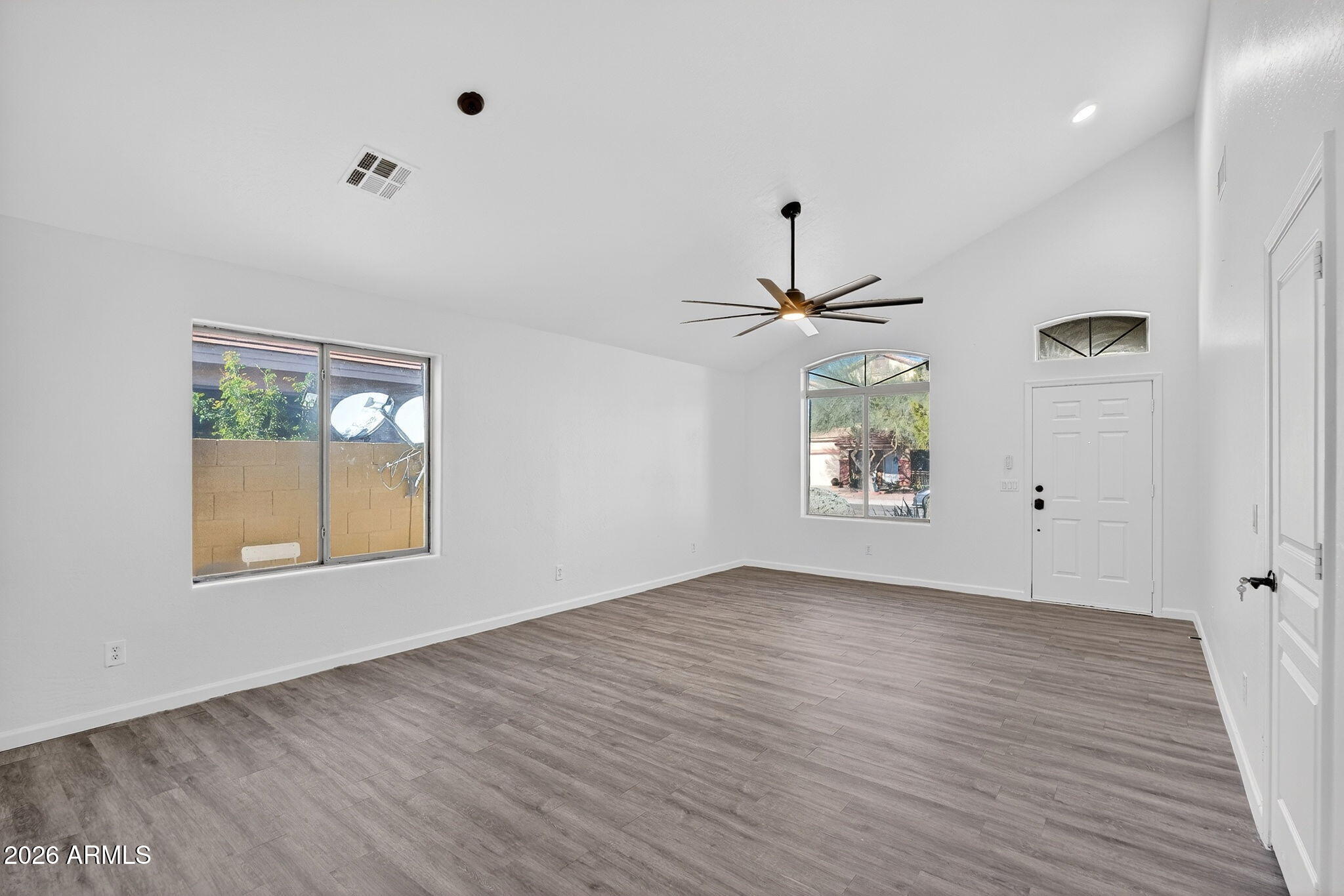 46039 West Amsterdam Road Maricopa, AZ 85139 - Photo 5 of 61 an empty room with wooden floor a ceiling fan and windows