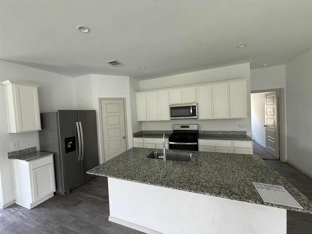 6710 Riplee Street Beaumont, TX 77708 - Photo 5 of 15 a kitchen with stainless steel appliances granite countertop a refrigerator a stove a sink and white cabinets