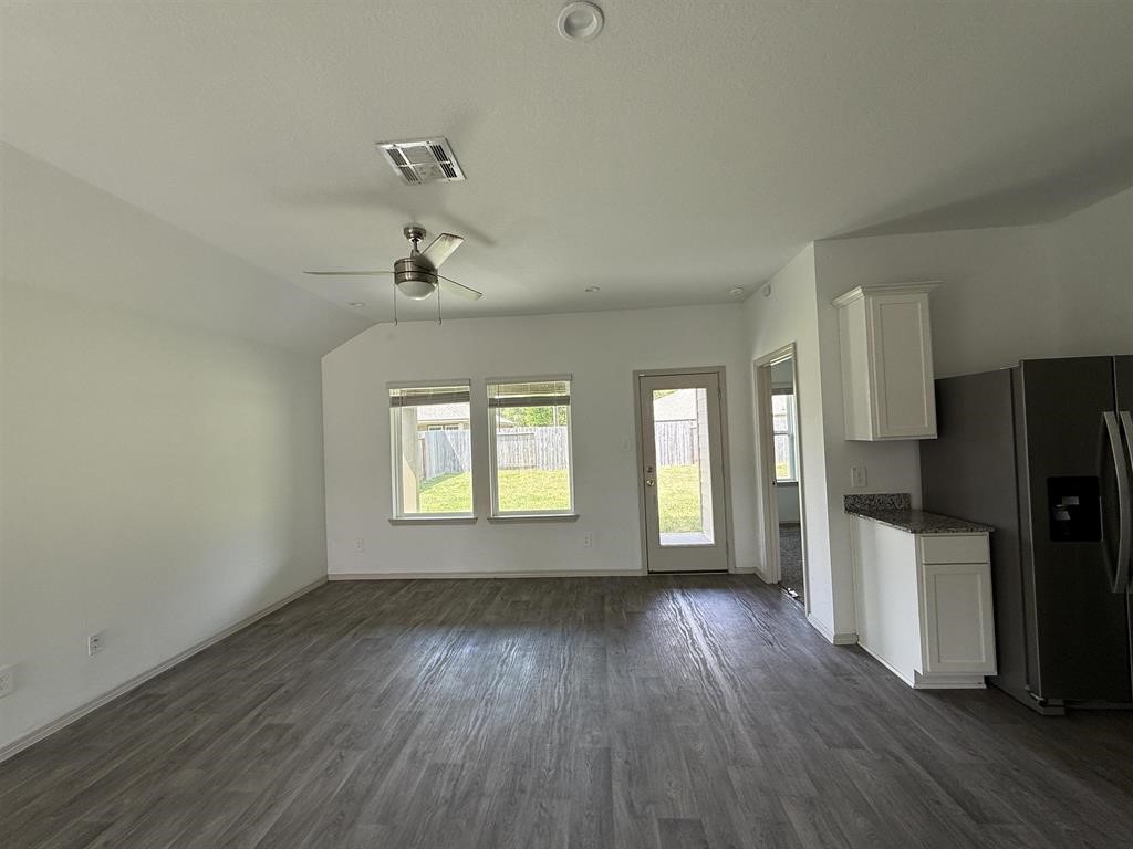 6710 Riplee Street Beaumont, TX 77708 - Photo 9 of 15 an empty room with wooden floor a ceiling fan and windows