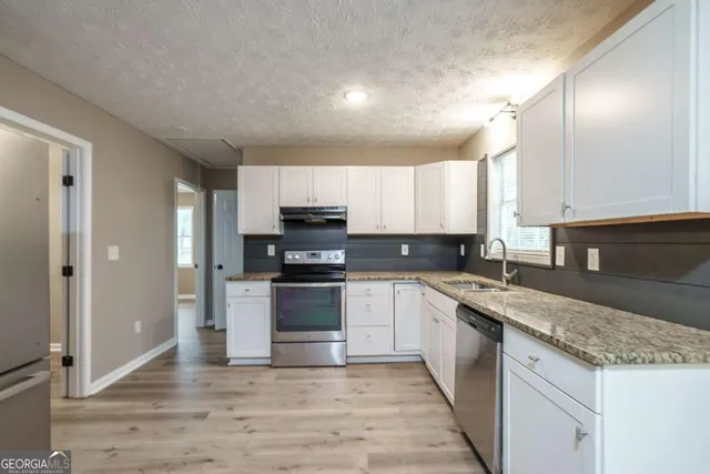 a kitchen with stainless steel appliances granite countertop a stove a sink and a refrigerator