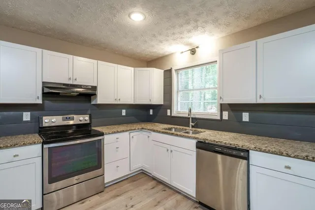 a kitchen with stainless steel appliances granite countertop a sink a stove a microwave and cabinets