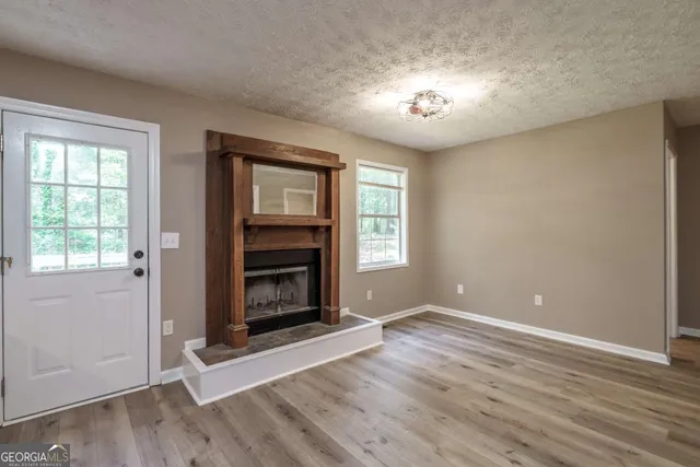 an empty room with wooden floor fireplace and windows