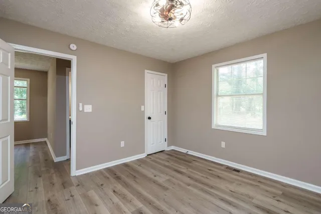 an empty room with wooden floor closet and windows