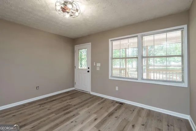 a view of an empty room with wooden floor and a window