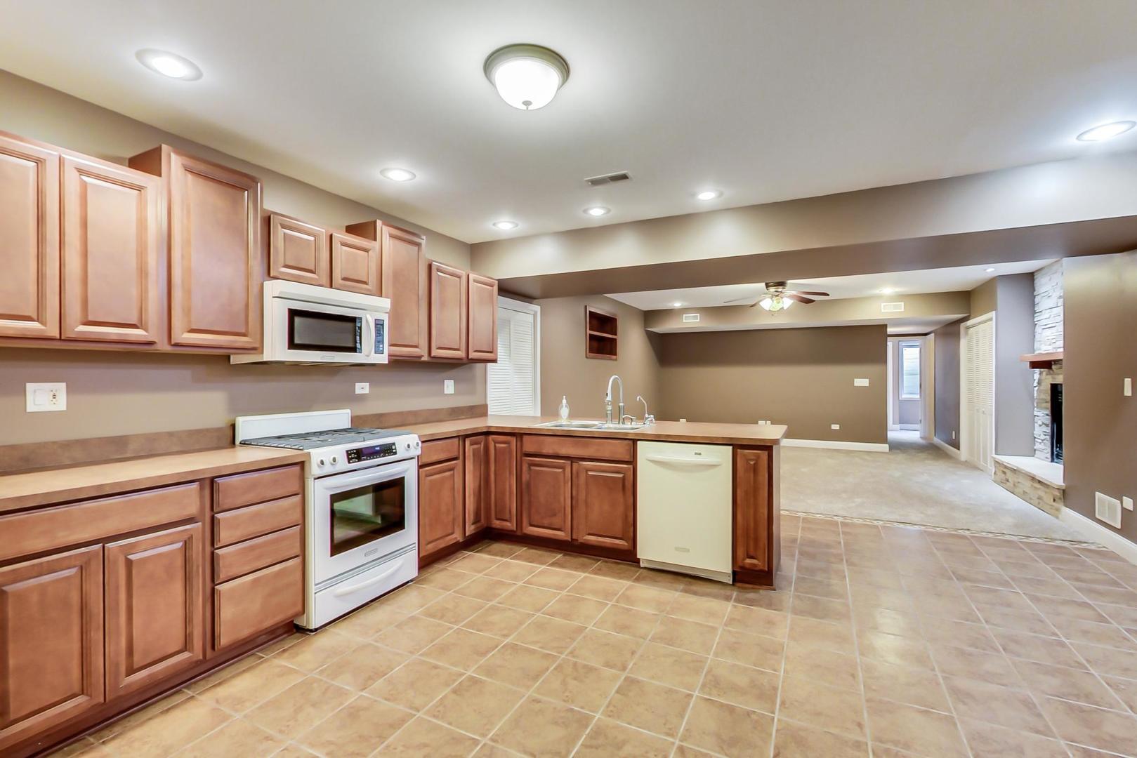 8901 Maple Avenue Burr Ridge, IL 60527 - Photo 40 of 68 a large kitchen with stainless steel appliances granite countertop a large stove top oven a sink dishwasher a dining table and chairs with wooden floor