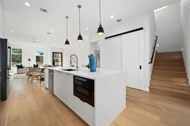 a kitchen with stainless steel appliances granite countertop a sink a stove and a wooden floor