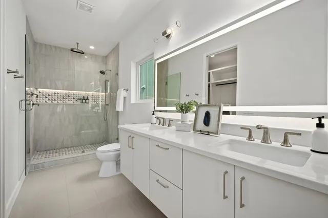a bathroom with a double vanity sink toilet mirror and shower
