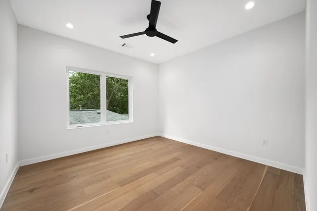 a view of an empty room with wooden floor and a window
