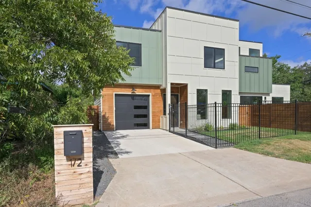 a front view of a house with glass windows and plants