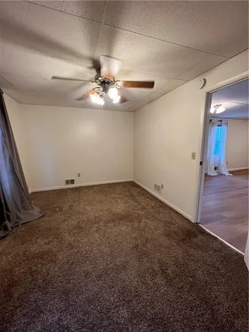 a view of an empty room with chandelier fan