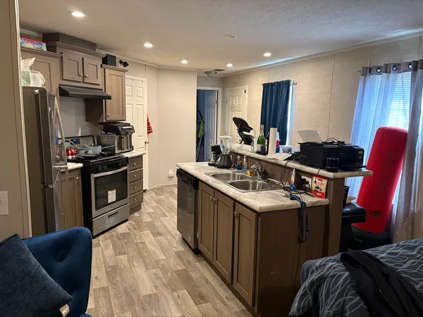 a kitchen with stainless steel appliances granite countertop a stove top oven a sink dishwasher a refrigerator and a dining table with wooden floor