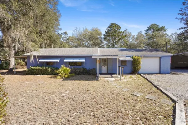 a front view of house with yard and trees in the background