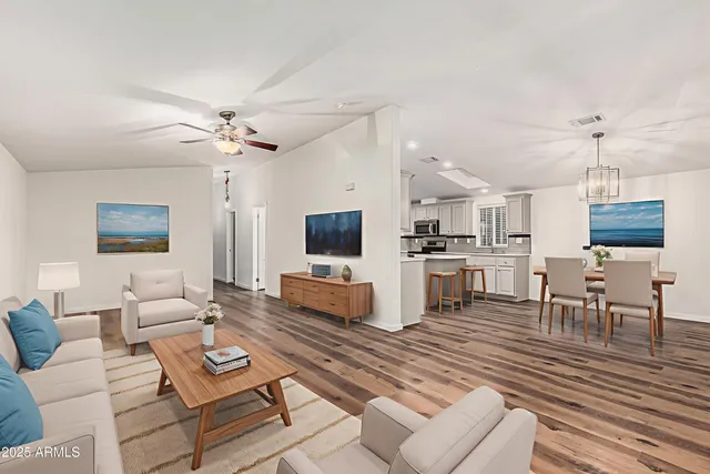 a living room with furniture kitchen view and a wooden floor