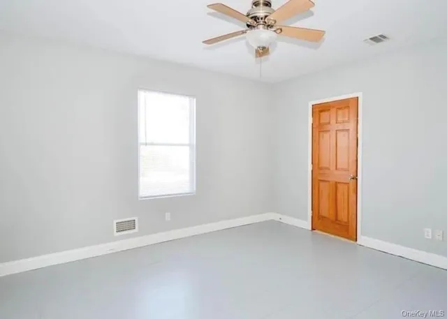 an empty room with a window and a fan