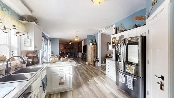 a room with stainless steel appliances kitchen island granite countertop a refrigerator and a sink