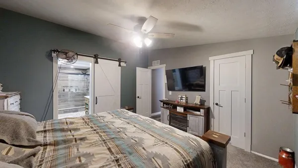 a bedroom with a bed and a flat tv screen on wall