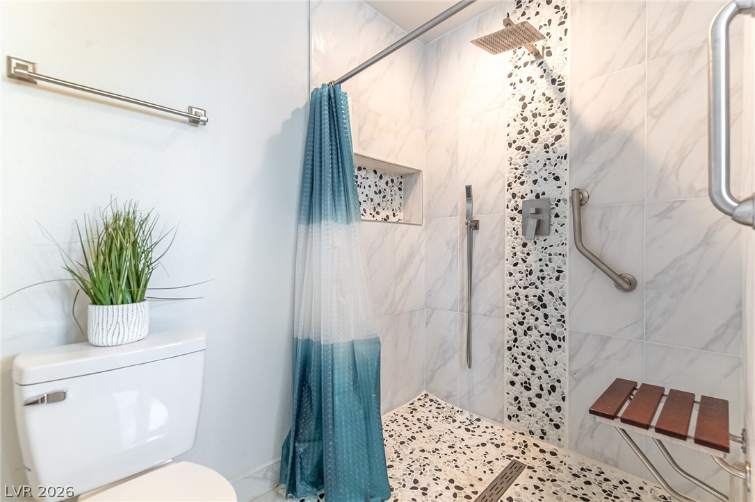 105 South Cimarron Road Las Vegas, NV 89145 - Photo 10 of 28 Custom tiling and a rainfall showerhead create a modern oasis in this accessible bathroom.