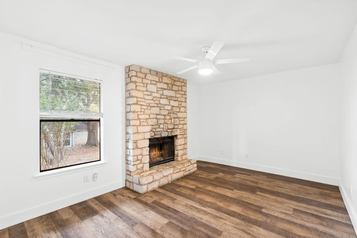 1712 Timber Ridge Road Austin, TX 78741 - Photo 16 of 35 Unfurnished living room featuring dark wood-style floors, a stone fireplace, and ceiling fan