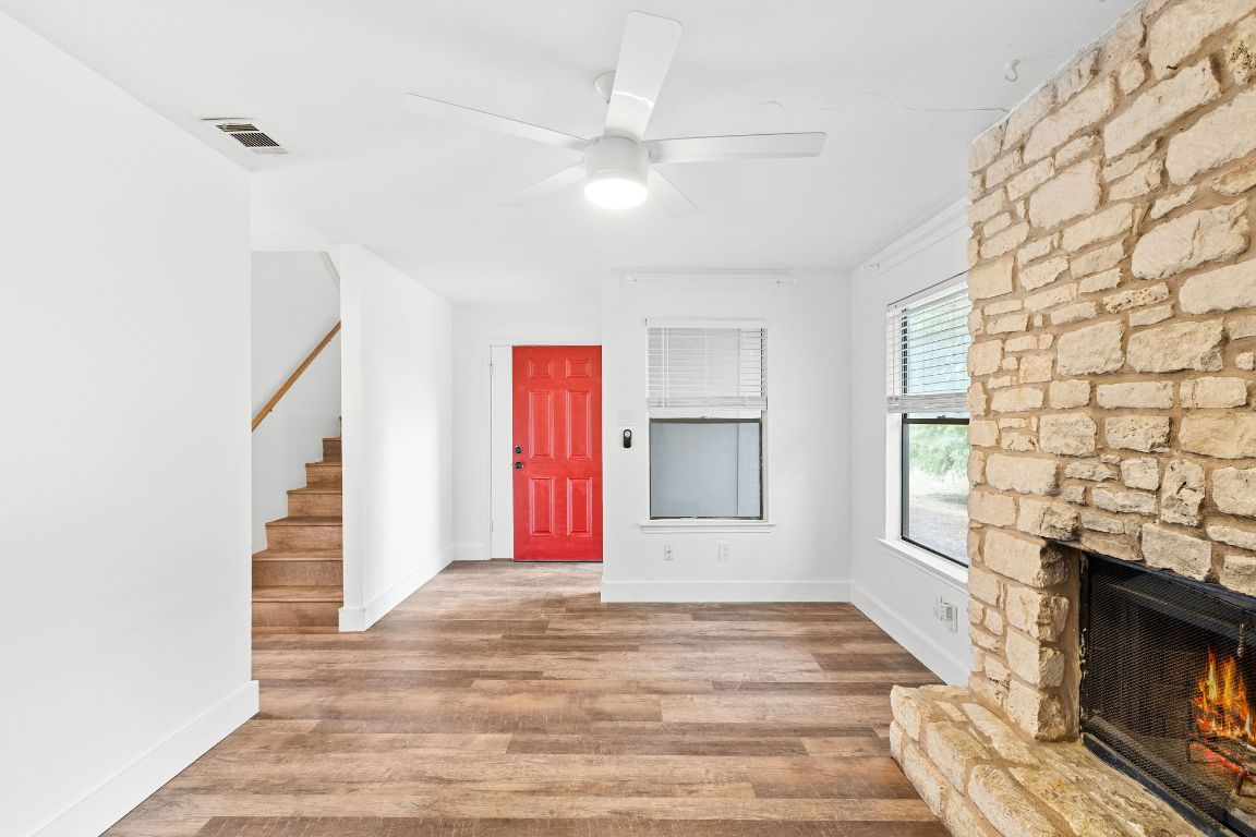1712 Timber Ridge Road Austin, TX 78741 - Photo 18 of 35 Entryway featuring light wood-style flooring, stairs, a stone fireplace, and ceiling fan