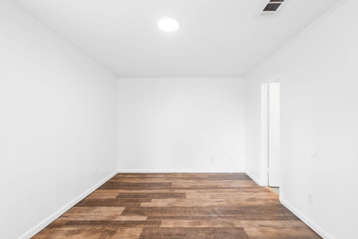 1712 Timber Ridge Road Austin, TX 78741 - Photo 24 of 35 Empty room with dark wood-type flooring and ornamental molding