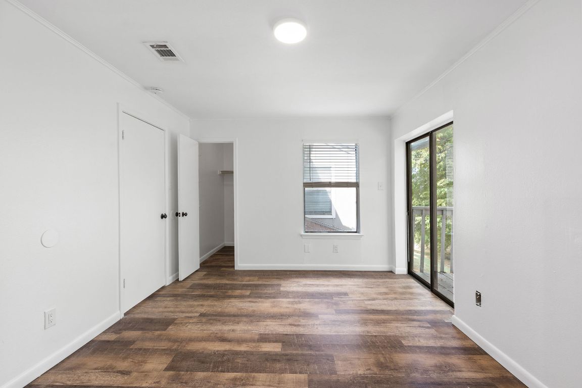 1712 Timber Ridge Road Austin, TX 78741 - Photo 26 of 35 Unfurnished bedroom featuring access to exterior, a spacious closet, dark wood-style floors, and crown molding