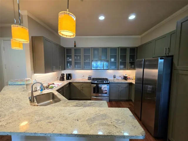 a kitchen with kitchen island granite countertop a sink and a refrigerator