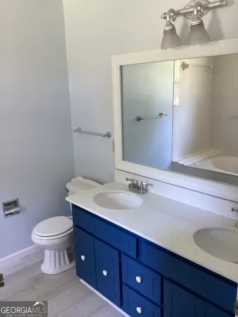 a bathroom with a granite countertop toilet a sink and a mirror
