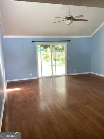 an empty room with wooden floor fan and windows