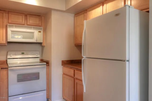 a white refrigerator freezer and a stove sitting inside of a kitchen