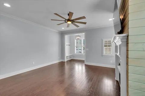 an empty room with wooden floor closet and windows