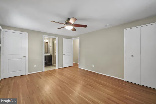a view of an empty room with wooden floor and a ceiling fan