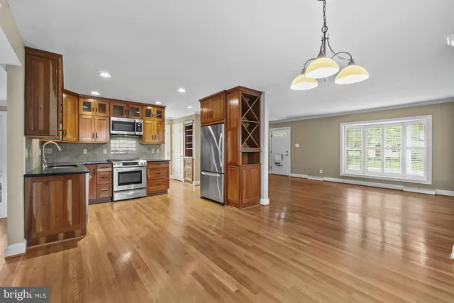 a kitchen with stainless steel appliances granite countertop a refrigerator a sink dishwasher a stove and white countertops with wooden floor