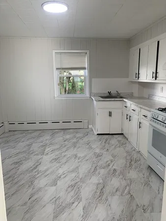 a room with a stove a sink and a window