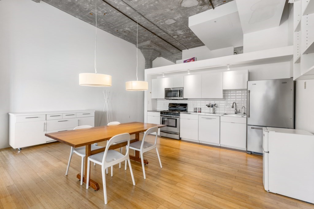 156 Porter Street, Unit 249 Boston, MA 02128 - Photo 7 of 30 a kitchen with stainless steel appliances kitchen island granite countertop a table chairs stove and white cabinets