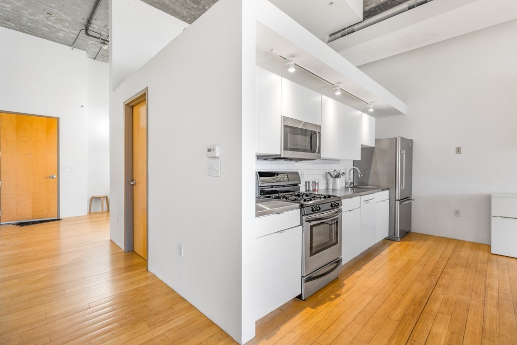156 Porter Street, Unit 249 Boston, MA 02128 - Photo 9 of 30 a kitchen with stainless steel appliances a stove a sink a refrigerator white cabinets and wooden floor