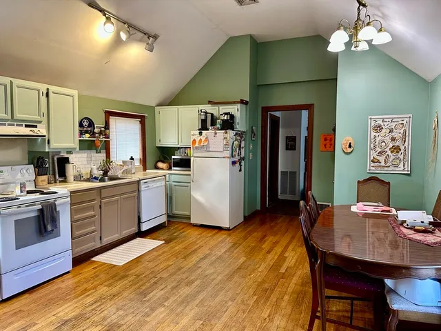 a kitchen with stainless steel appliances granite countertop a stove a refrigerator a sink dishwasher a dining table and chairs with wooden floor