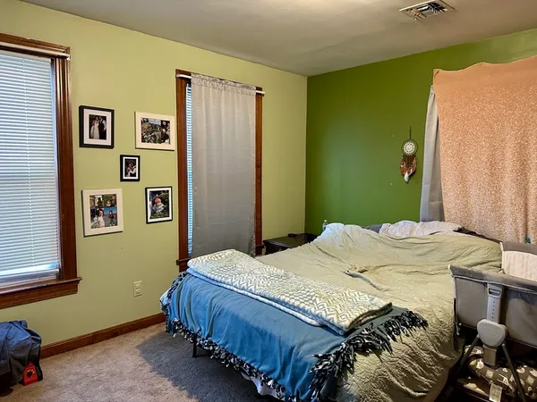 a bedroom with a bed and painting on the wall
