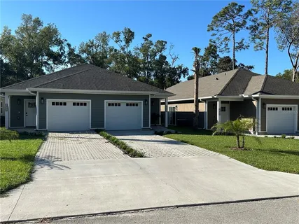 a front view of a house with a garden and trees