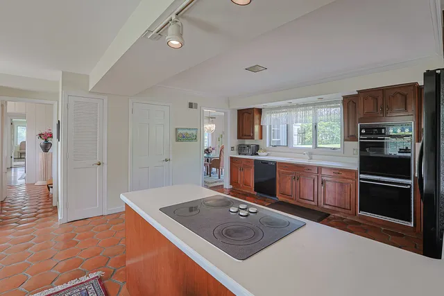 a kitchen with stainless steel appliances granite countertop a refrigerator a stove and a sink with wooden floor