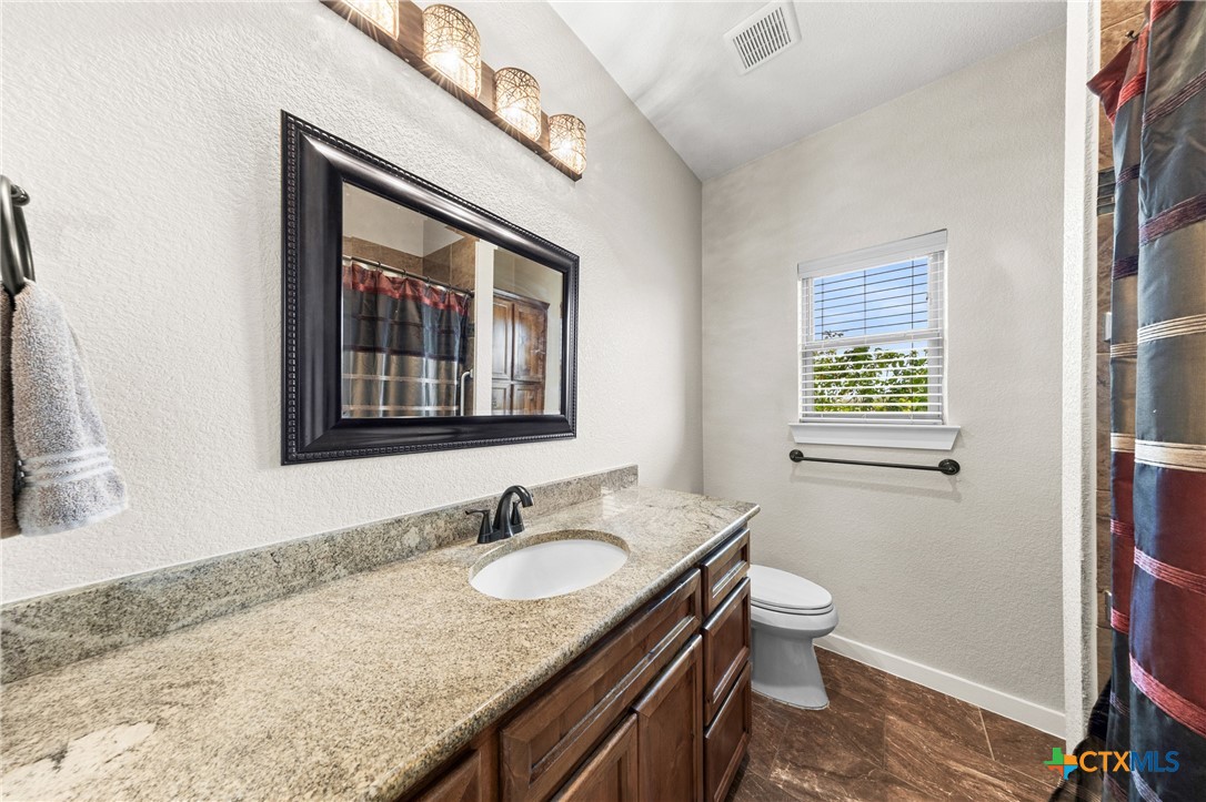 452 County Road 470 Chilton, TX 76632 - Photo 12 of 47 a bathroom with a granite countertop sink a mirror and a toilet