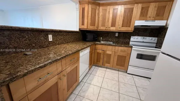 a kitchen with granite countertop a sink a stove and cabinets